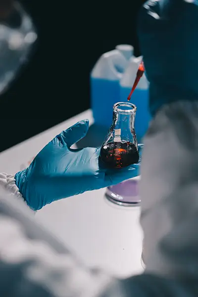 a person in a lab coat holding a glass with liquid